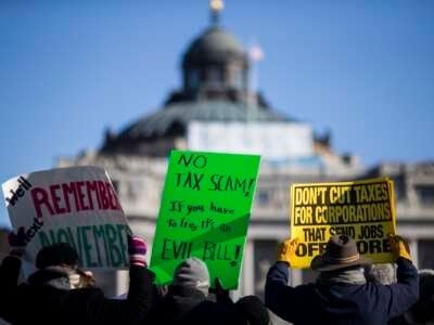 Demonstrators hold signs during a rally against the Republican tax plan on December 13, 2017 in Washington, D.C.