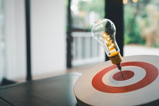 Light bulb with arrow of darts on dart board. Concept of finding problem solving or business development, key to success.