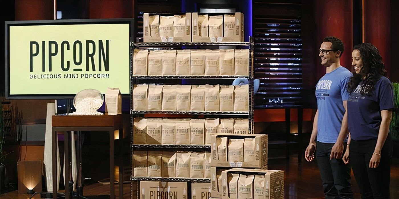 A man and woman standing beside beige bags of popcorn with the Pipcorn sign on a screen while pitching on Shark Tank