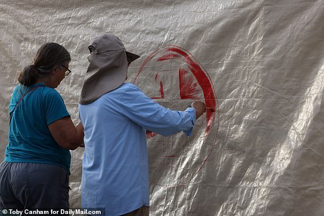 Humanitarian aid workers paint a tent with a red cross at the hole in the border wall east of Sasabe