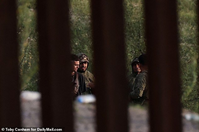 Apparent cartel human smugglers 'coyotes' stand guard on the Mexico side of the U.S.-Mexico border waiting for an opportunity to drop migrants into the U.S. at an area where the massive border wall ends in rural Pima County, Arizona