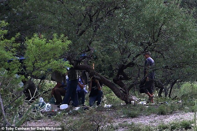 A group of migrants and smugglers set up shop just yards from a hole in the border wall