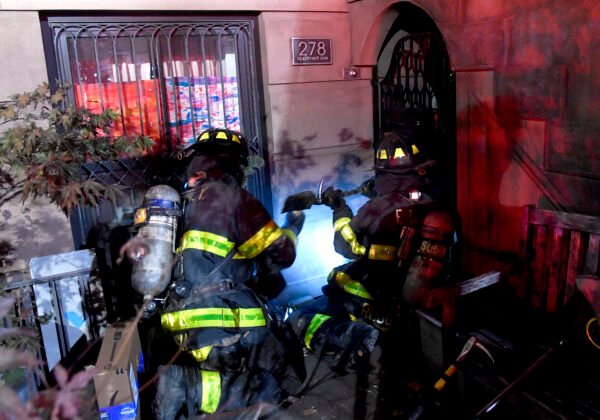 Firefighters use a Halligan tool to force open the gate barring the garden level door on Henry Street on Oct. 13. Photo courtesy of Marc Hermann