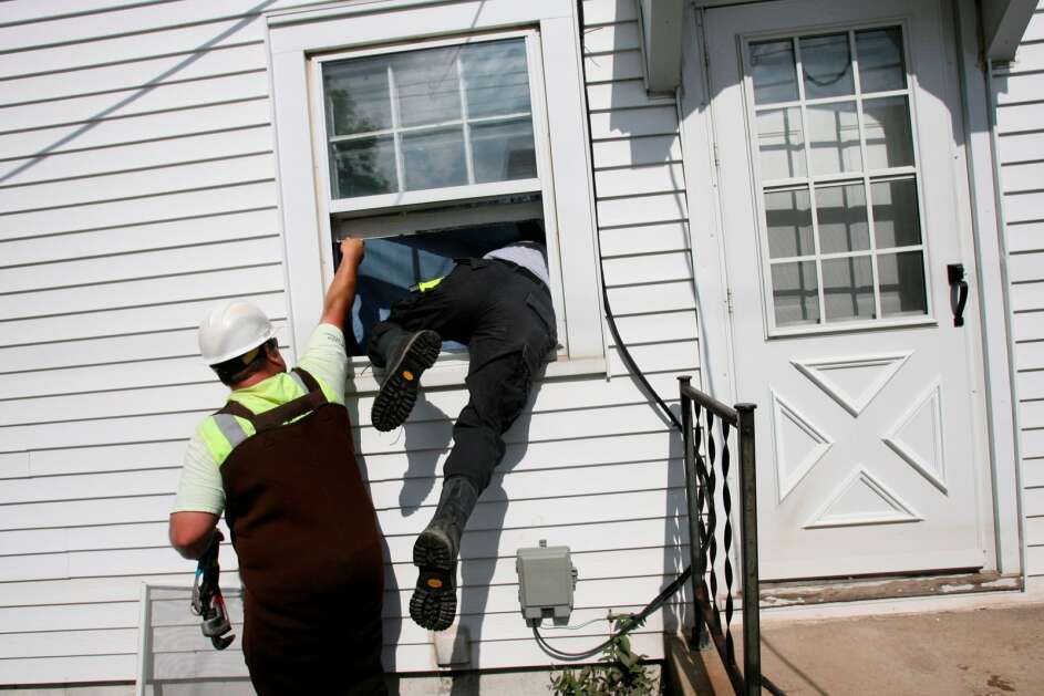 Eric Vandewater, a member of the urban search and rescue unit Iowa Task Force One, climbs through a window of an evacuated house in Cedar Rapids, Iowa, Sunday, June 15, 2008. Emergency and utility crews began the process of examining each house in the flood zone to make sure they were safe for residents to return. (AP Photo/Seth Wenig)