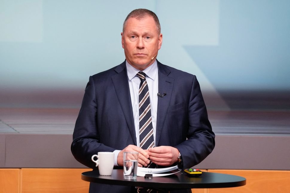 Man dressed in suit and tie stands at small black desk