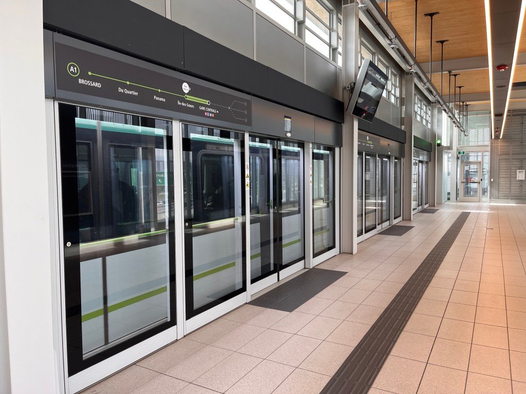 The clean interior of a light rail station, with automatic glass doors and a tile floor clear of any debris or garbage.