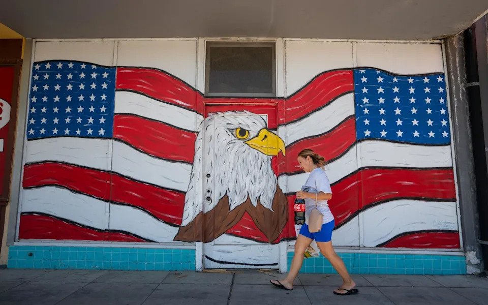 A woman walks by a mural of an eagle head and an American flag