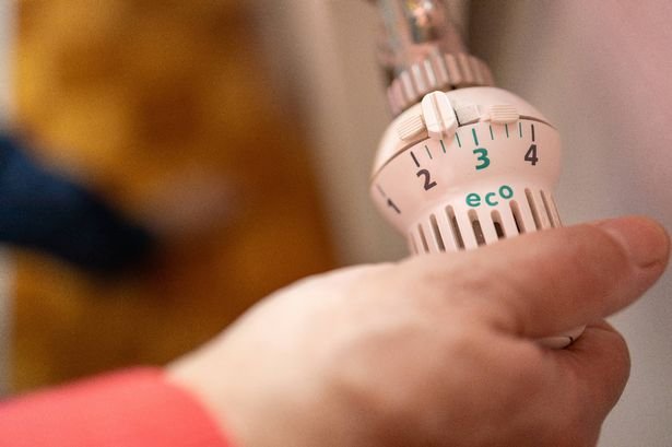 A man's hand turns the battery-powered radiator. Eco mode. Heating in an apartment, at home. Heating prices.