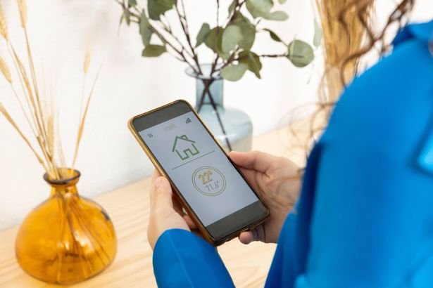 Close-up view of woman controlling home heating from her smart phone. Female home owner checking energy consumption.