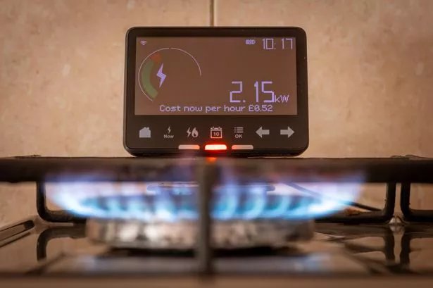 A energy use and cost concept with a smart energy meter close by a gas cooker.
