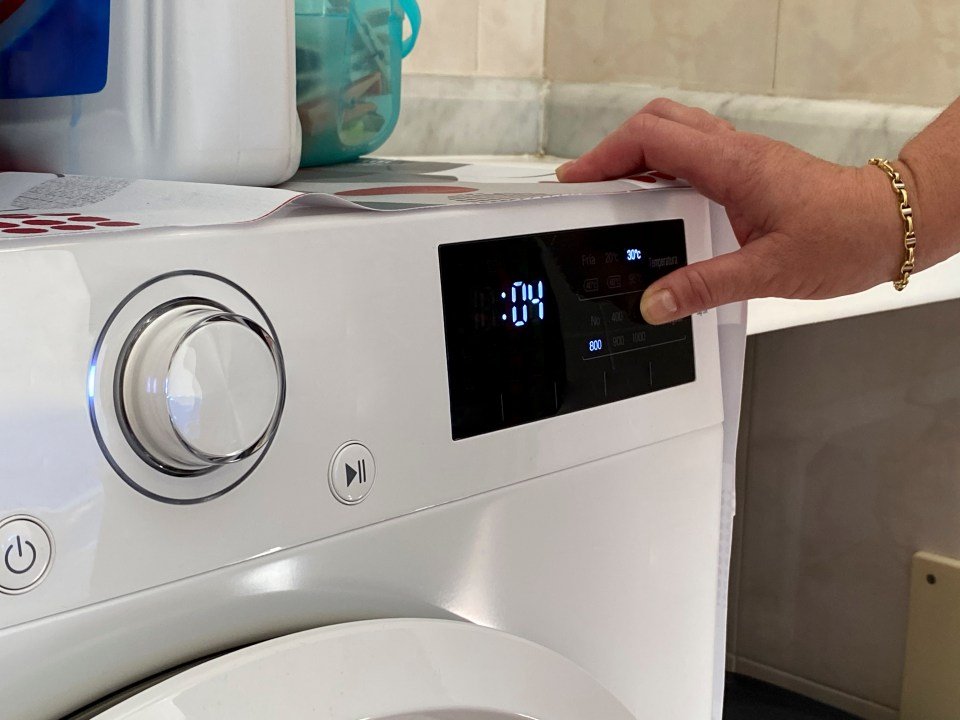 Woman's hand using a washing machine's control panel.
