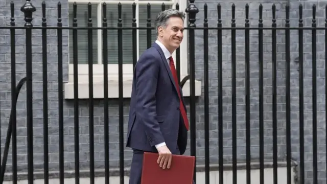 Ed Miliband leaving Downing Street, carrying a red folder and wearing a navy suit and red time