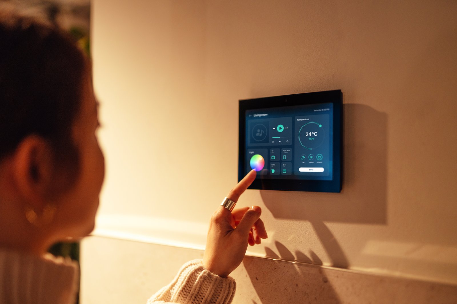 Young woman activating home automation system with a smart home device showing temperature, light, and appliance controls.