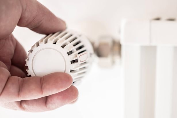 Human hand adjusts thermostat on a heater