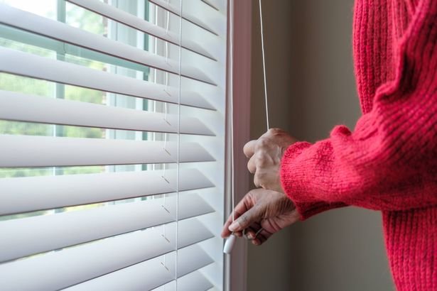 Close-up of unrecognizable black woman opening/closing window blind