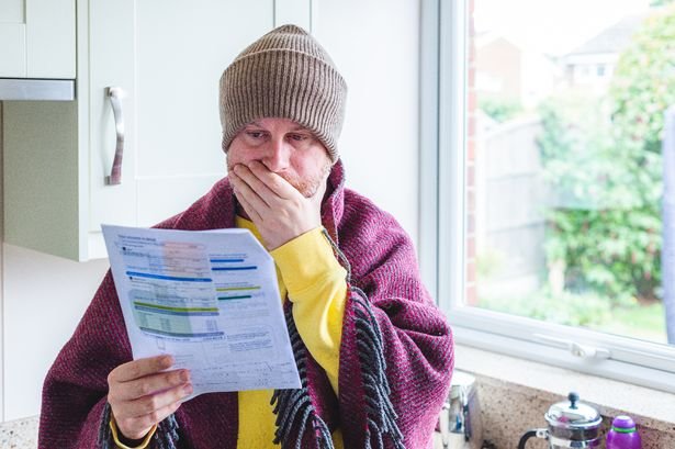 Man reading energy bill while wearing beanie