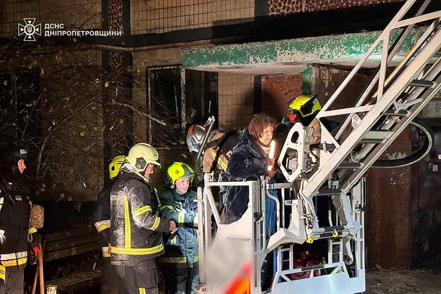 Firefighters evacuate a resident following the Russian rocket attack that hit a multi-storey apartment building in Dnipro