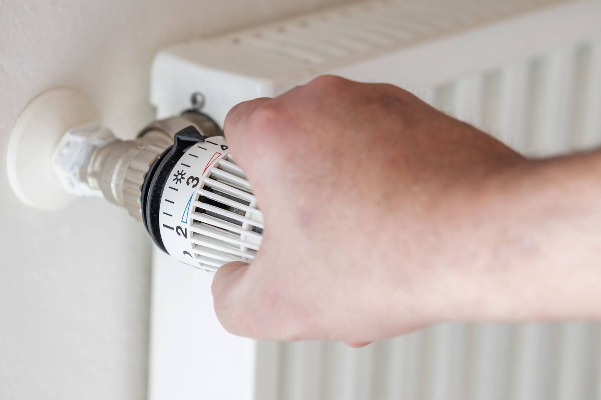 Human hand adjusts thermostat on a heater
