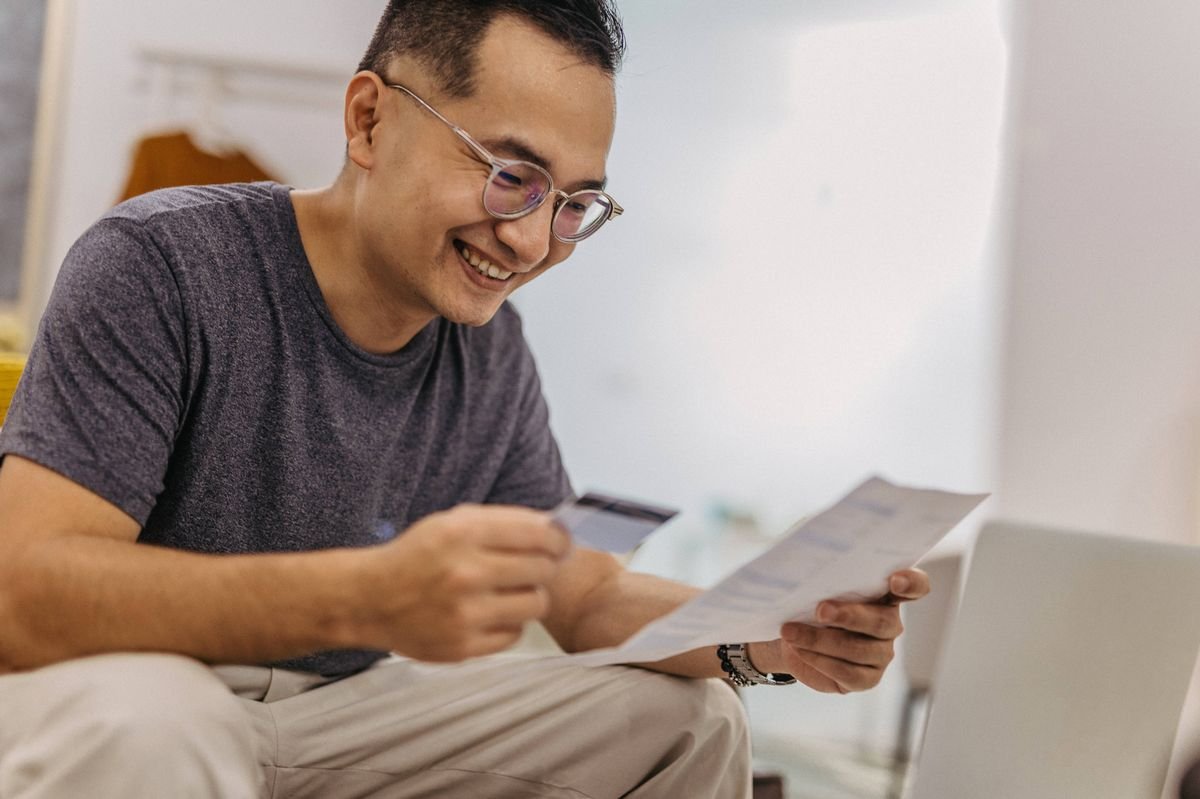 View of smiling mature man holding bill and credit card
