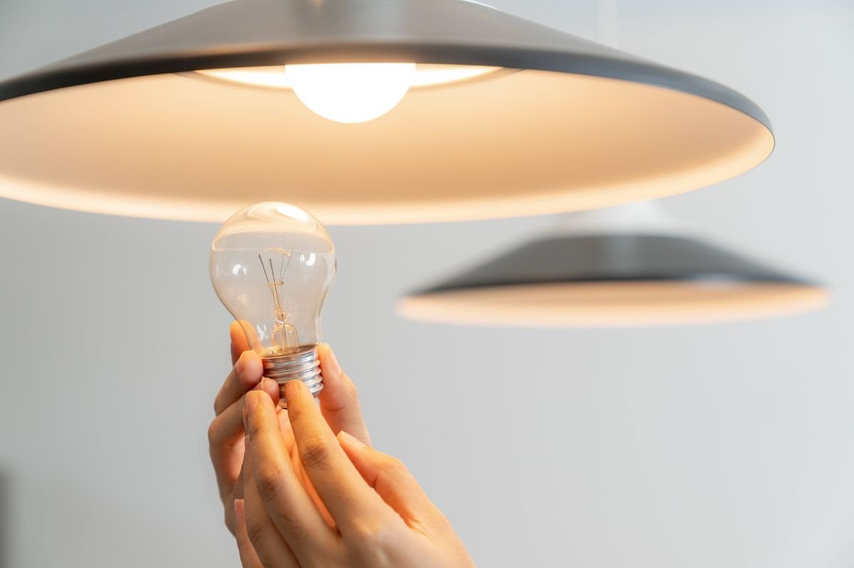 The young woman is changing light bulbs at home
