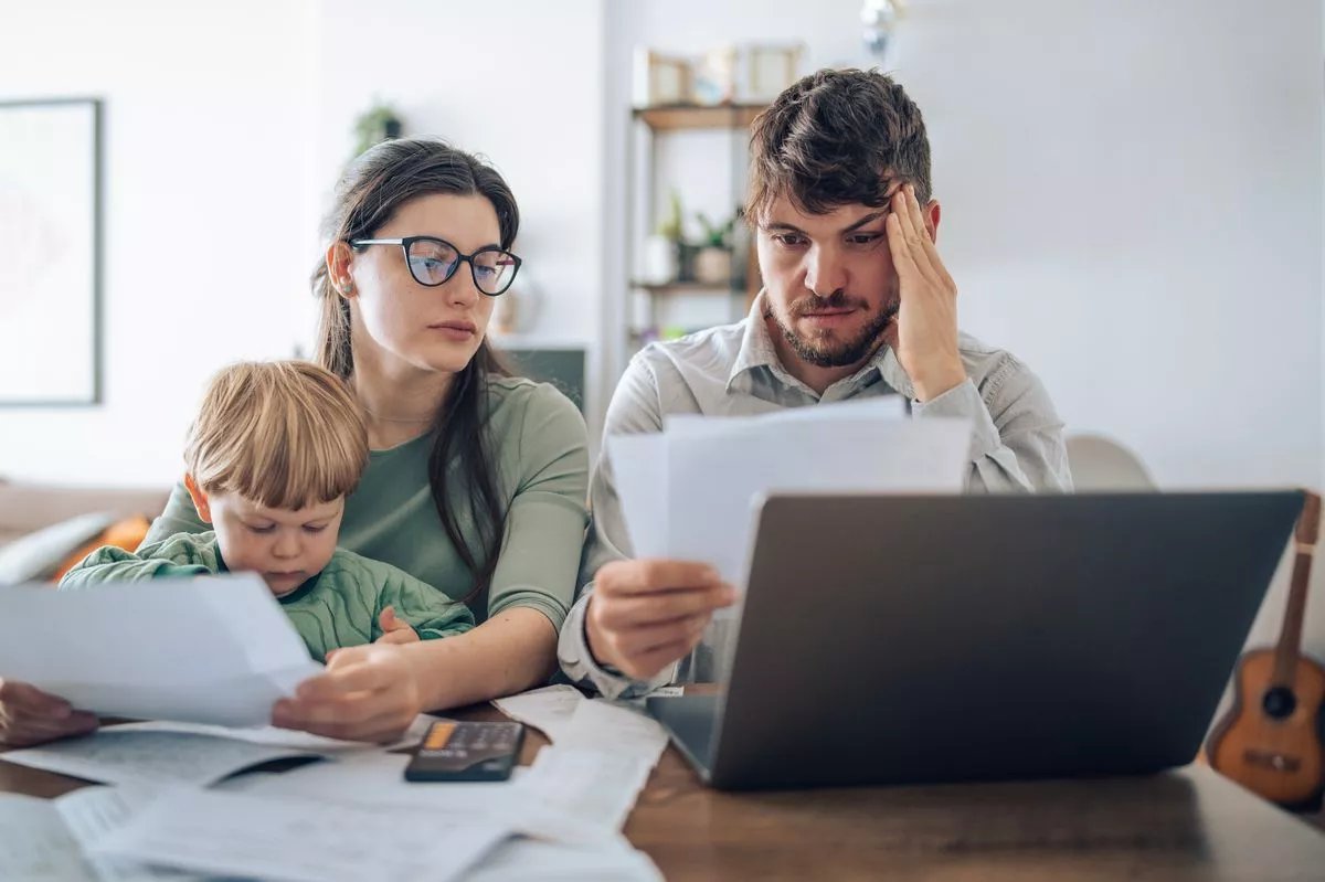Young family of three with a toddler managing their budget,paying bills and taxes online and calculating monthly expenses at home.Inflation concept.