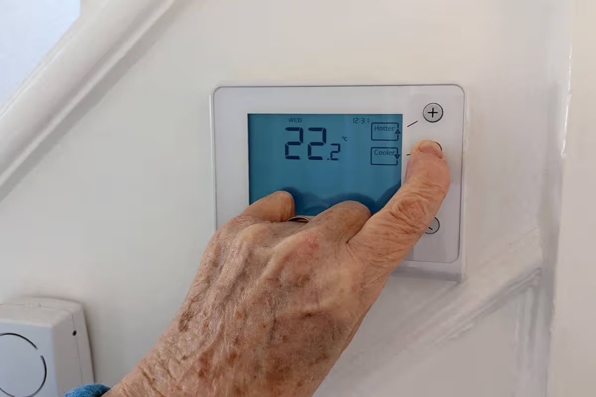 Elderly person turning down the central heating with a wireless thermostat