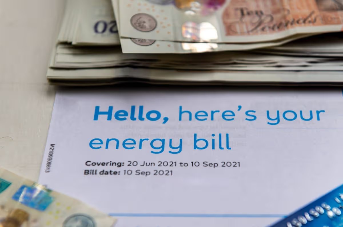Close up of a energy bill with a pile of bank notes and a payment card. Rising energy cost concept.