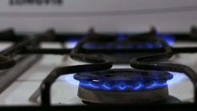 A gas cooker is turned on, exposing the blue naked flame.