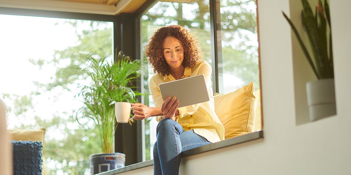 Woman sitting by the window looking at her energy account on a tablet