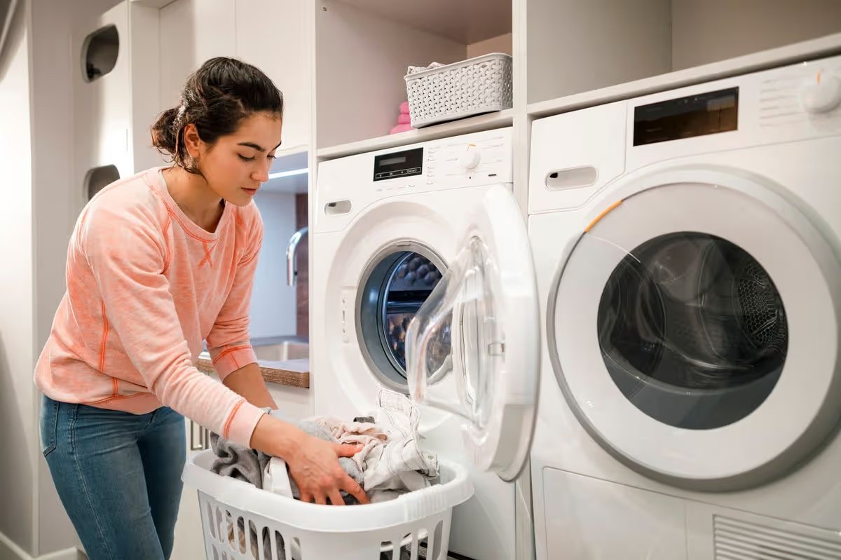 Woman doing her laundry while at home in the Northeast of England. She is taking out the clothes and putting them into a laundry basket.