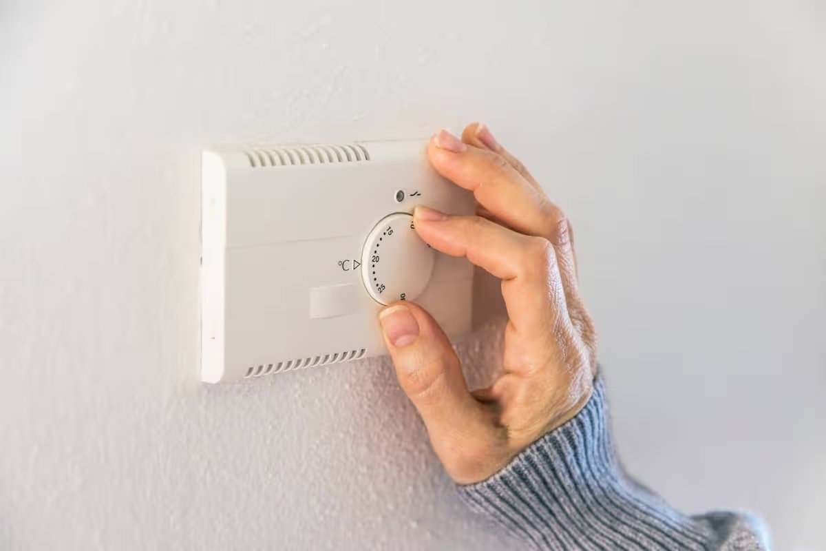 Woman controlling the temperature of the house with thermostat in Pergine Valsugana TN Italy.