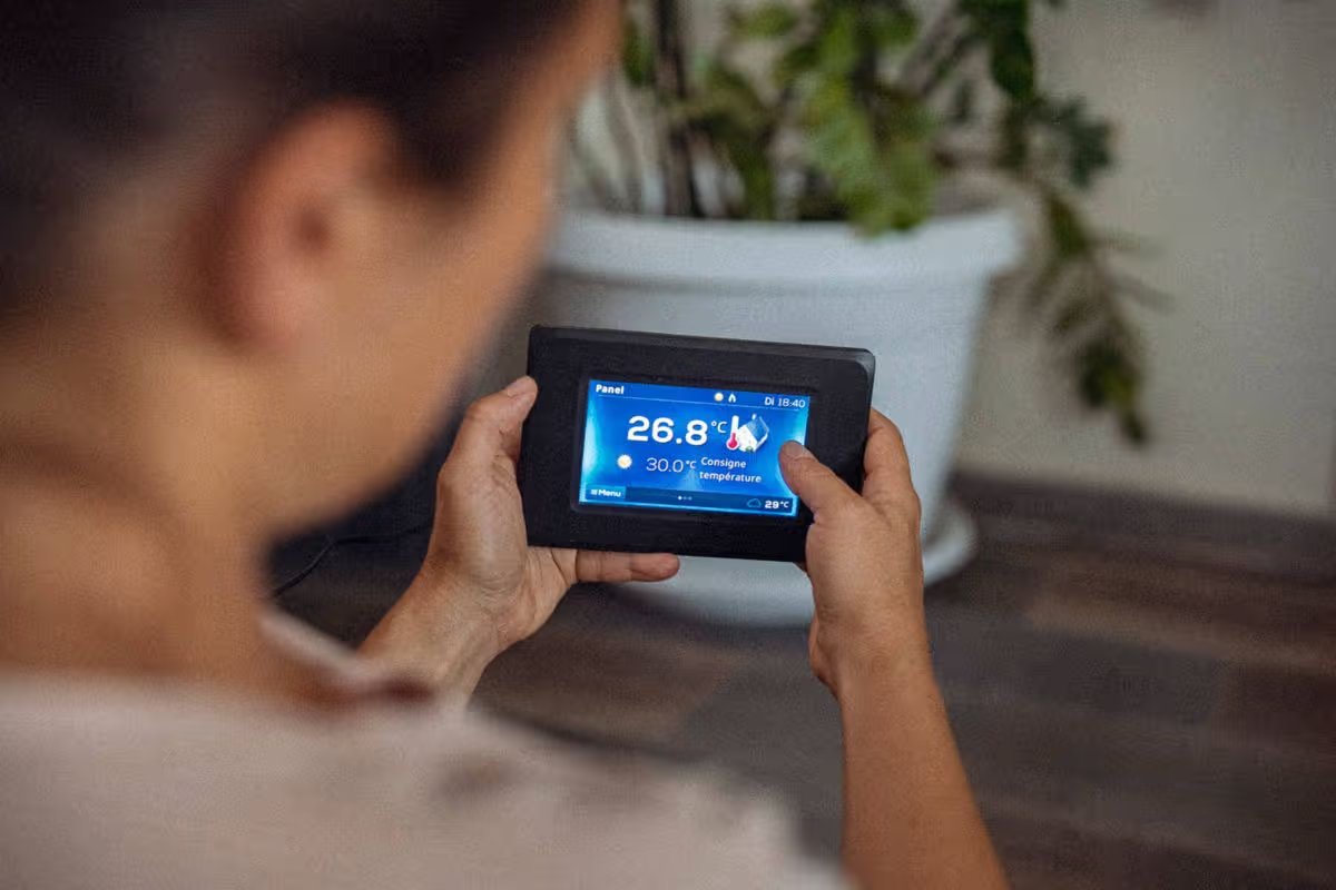 Using energy at home. Point of view of woman using smart control of the thermostat of heat pump, changing settings. Ease of use of artificial intelligence in everyday life