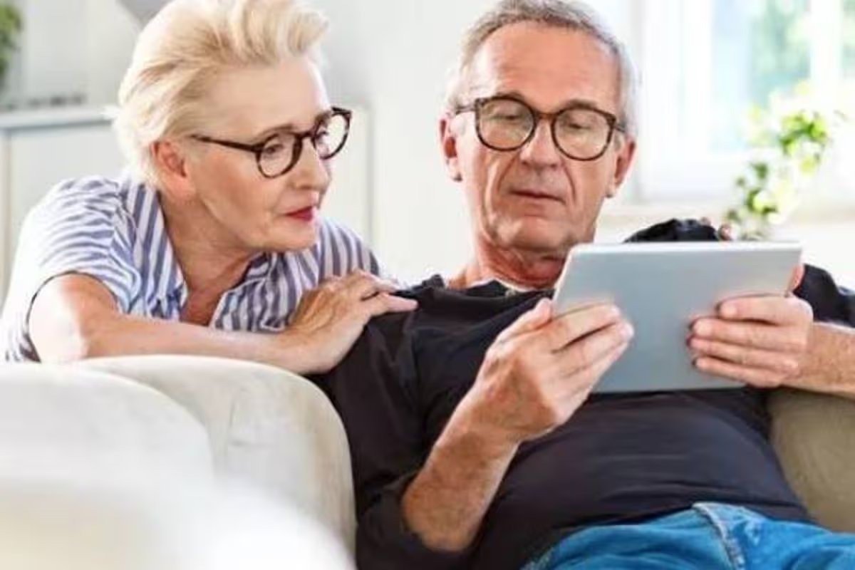A smiling mana and woman are looking at a tablet screen 