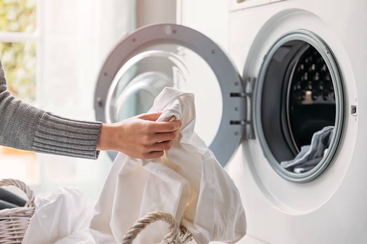 Close up of female hands dropping dirty laundry in the washing machine