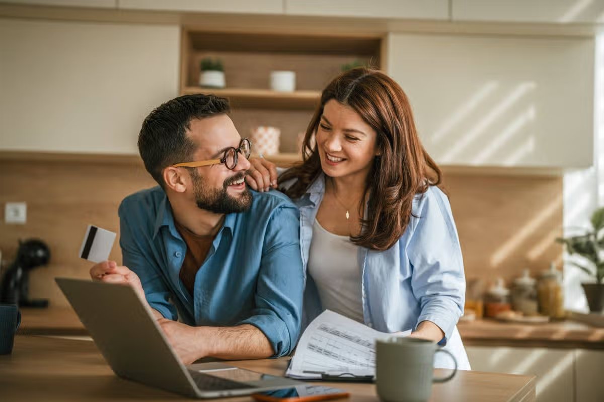 Happy couple calculating expenses, paying bills