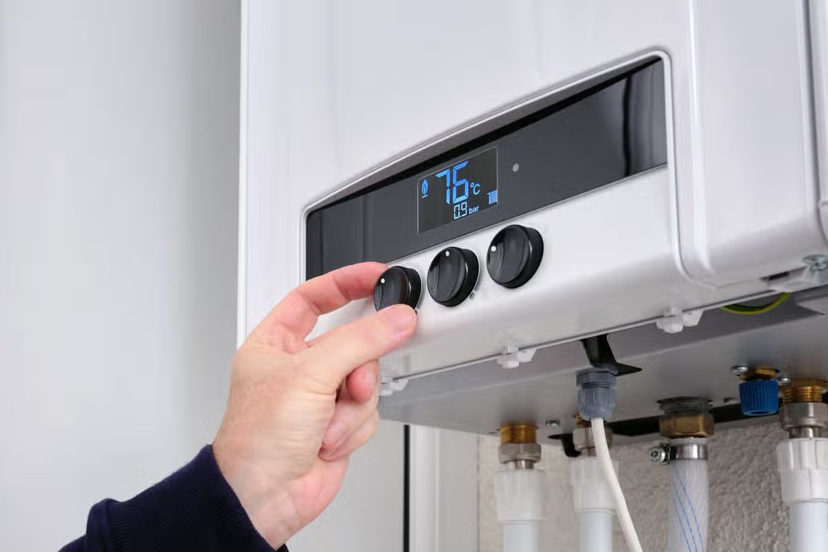 Close up of a man's hand changing the temperature on a modern digital gas boiler.