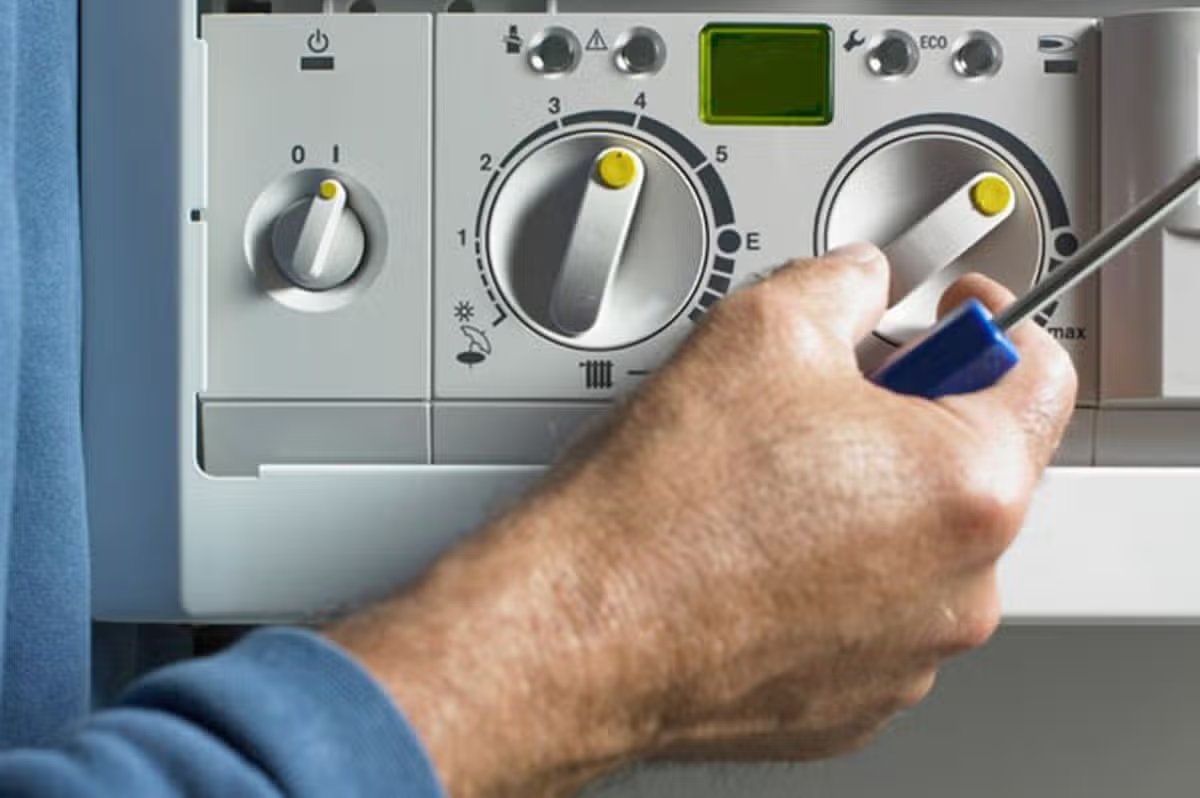 A person is adjusting settings on a boiler 